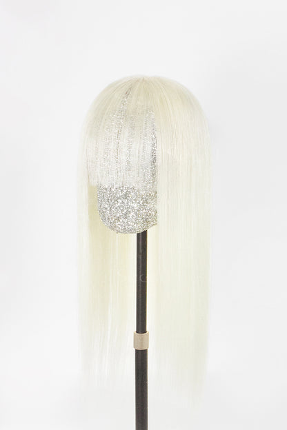 A long, straight platinum blonde wig with a textured silver glitter crown and a glittery silver lower section, displayed on a black mannequin stand against a white background.