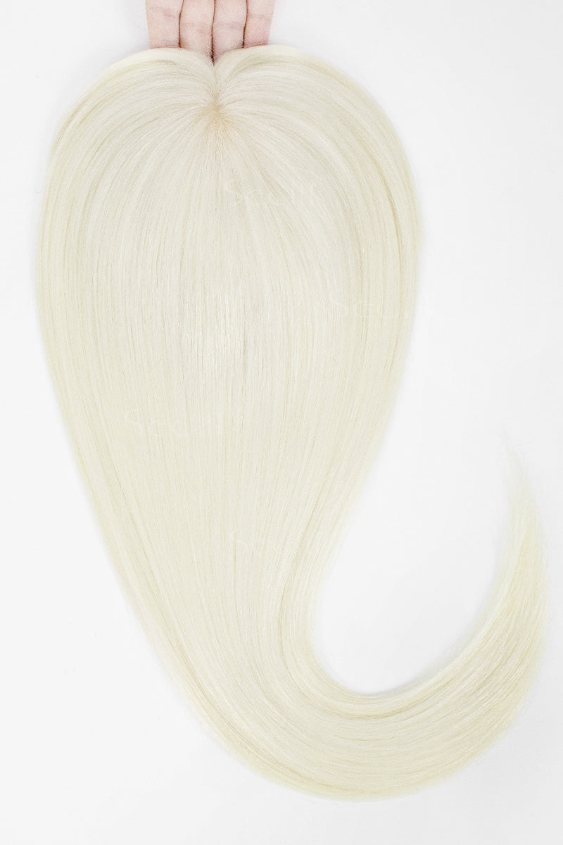 A hand holds up a long, straight synthetic hair extension piece in a very light platinum blonde color against a plain white background.