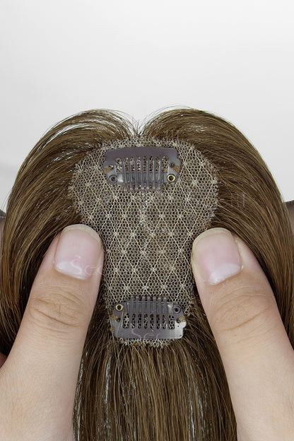 Brown hair topper with electronic mesh held between fingers against a white background