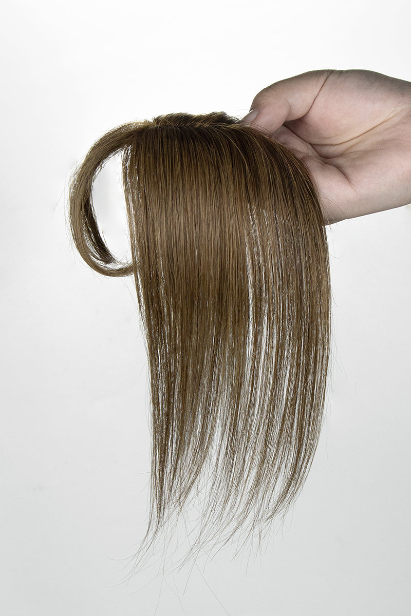 Brown hair topper held by a hand against a white background