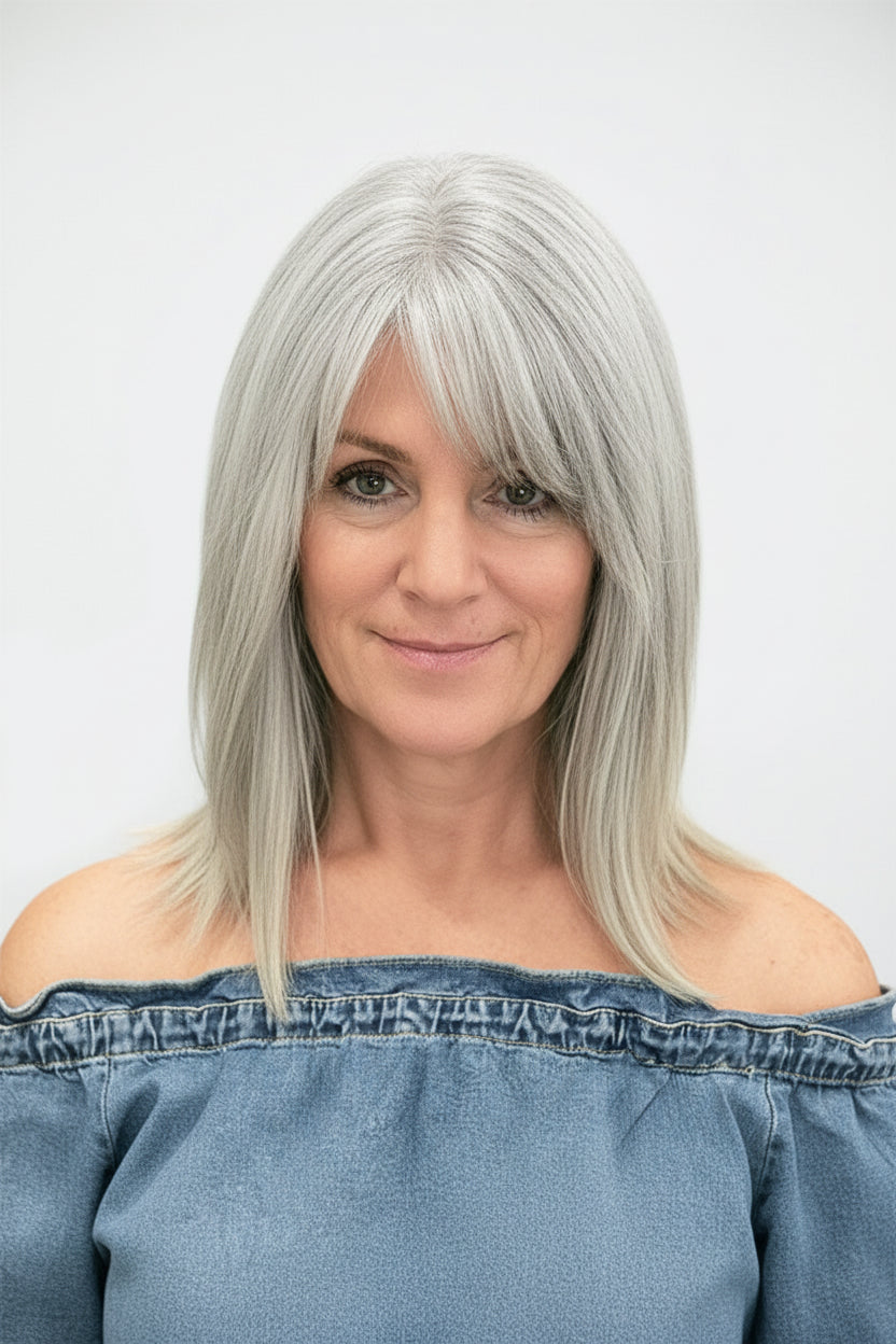 A woman with shoulder-length silver-gray hair and straight bangs, wearing an off-the-shoulder blue top against a plain light gray background.