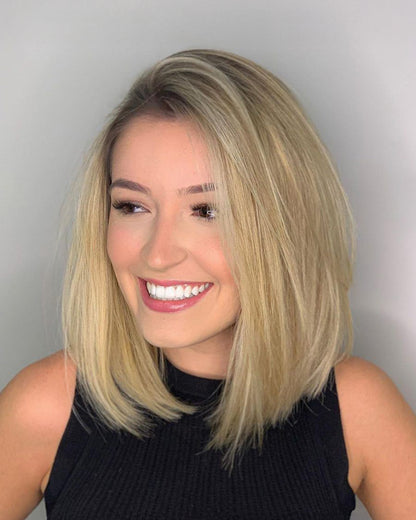 Woman with blonde hair and a black top against a plain background
